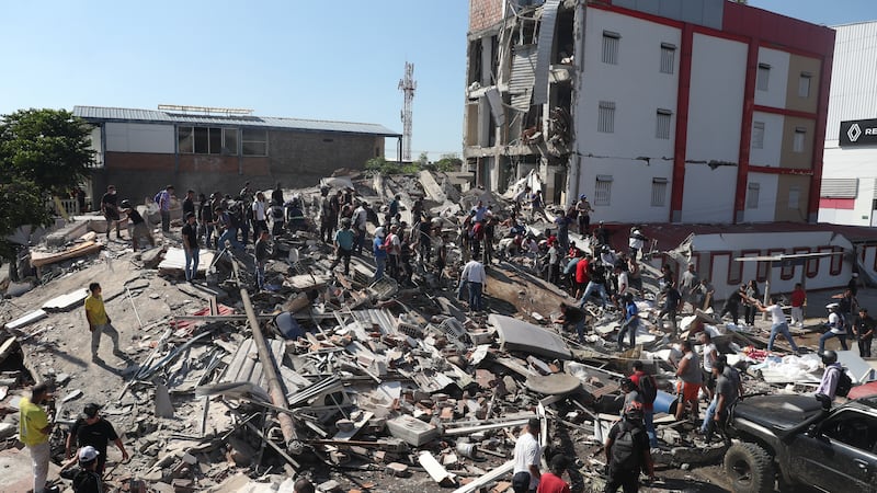 Residents and rescue workers search through the rubble of a collapsed building after an...